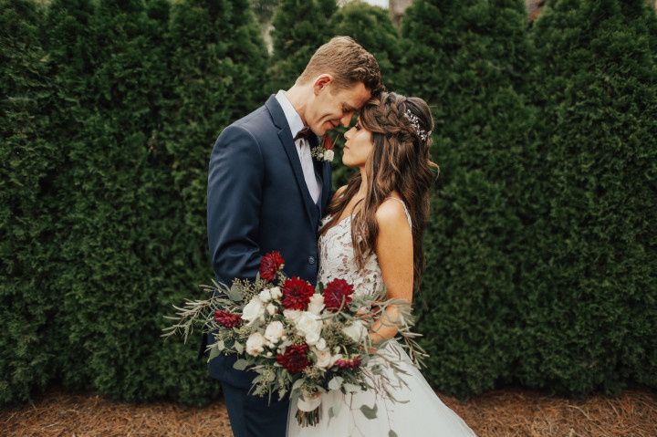 groom wearing navy blue suit poses with bride carrying bouquet
