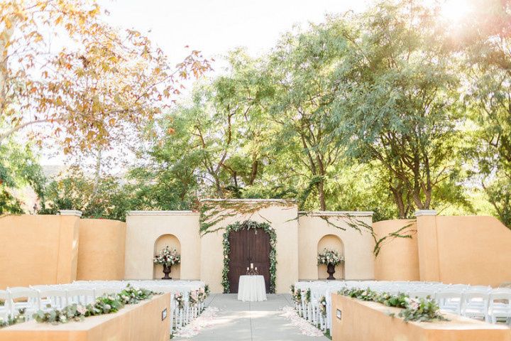 Los Robles Greens santa barbara wedding venue outdoor patio with rows of white chairs decorated with greenery floral garlands