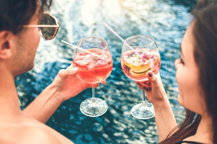 couple toasting cocktails in pool