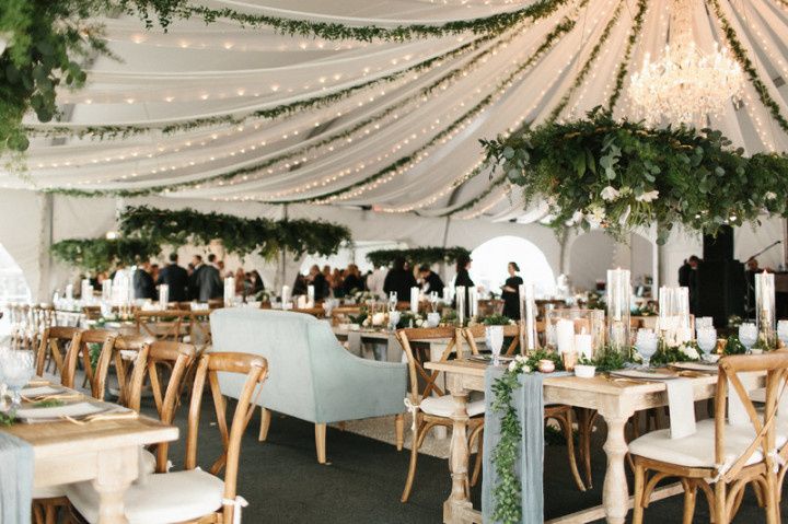 elegant garden-style wedding reception tent with greenery garlands and light strands