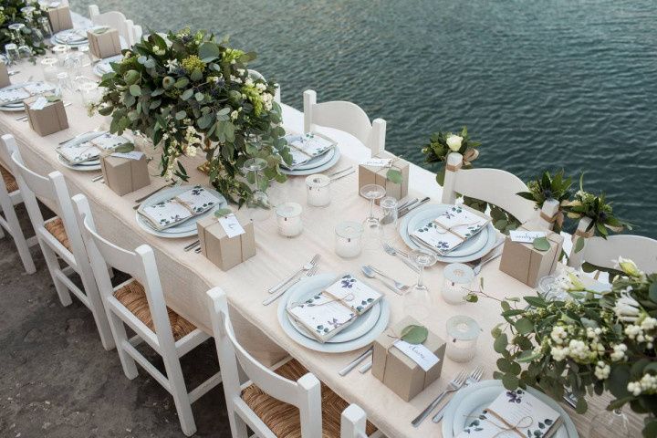 long wedding reception table at waterfront venue with greenery and pink centerpieces