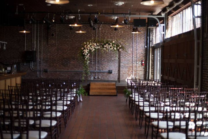 industrial wedding ceremony space with exposed brick and floral arch