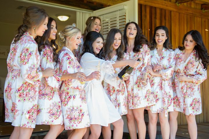bridesmaids wearing floral robes popping champagne