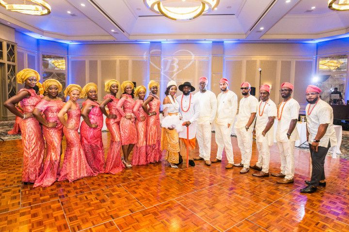 Different aso ebi styles are shown as Nigerian couples stands at a traditional wedding with their attendants. 