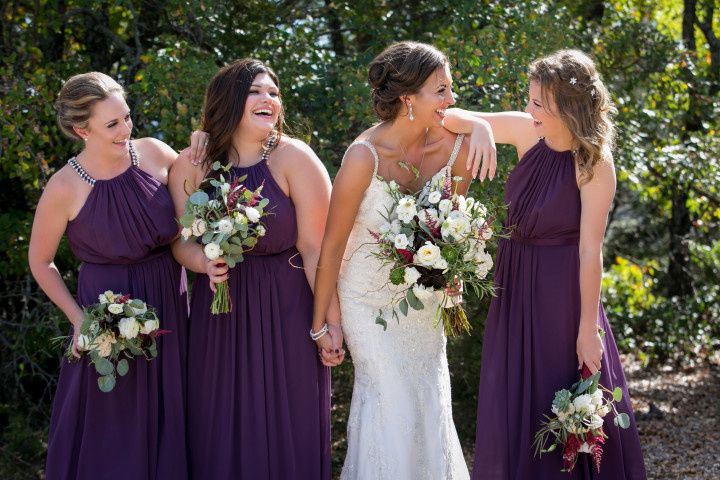 bridesmaids wearing purple dresses hugging bride