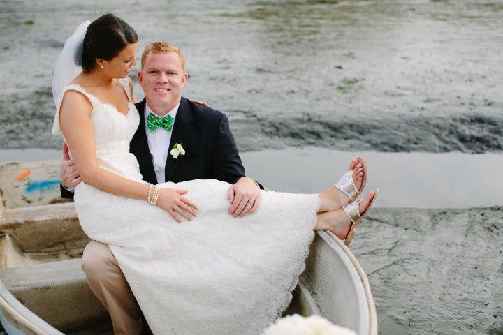 Bride sitting on groom's lap by water
