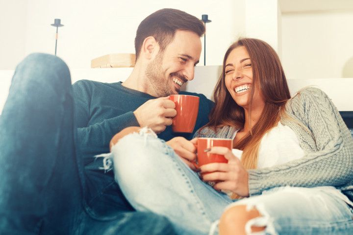 couple on couch holding red mugs