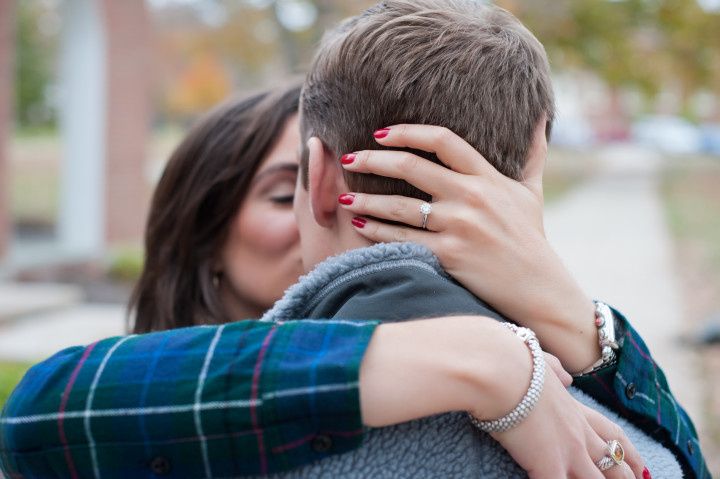 woman hugging man and showing off engagement ring