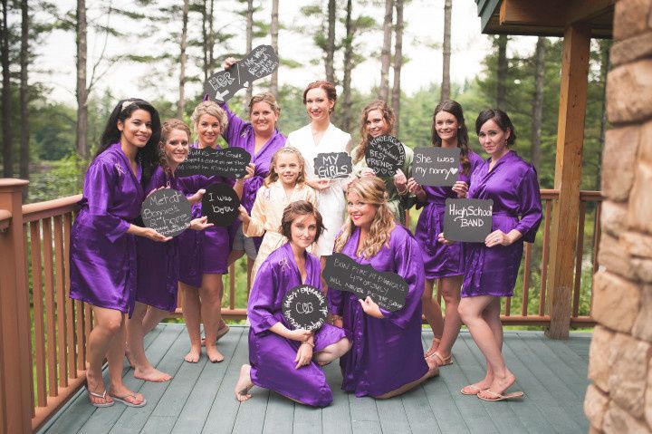 bridesmaids in purple satin robes holding chalkboard signs