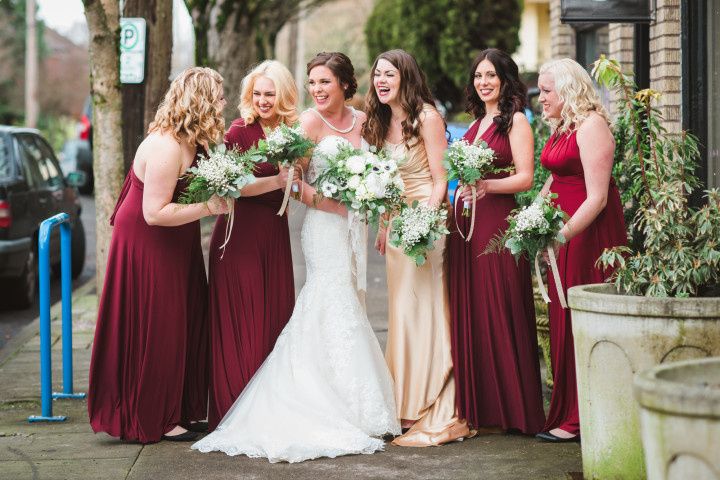 Bridal party laughing with bride in red dresses and bouquets 