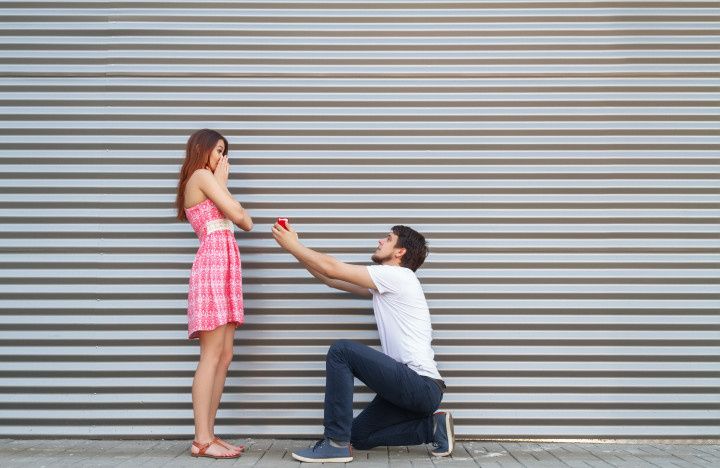 young couple proposing, man on one knee, woman in shock