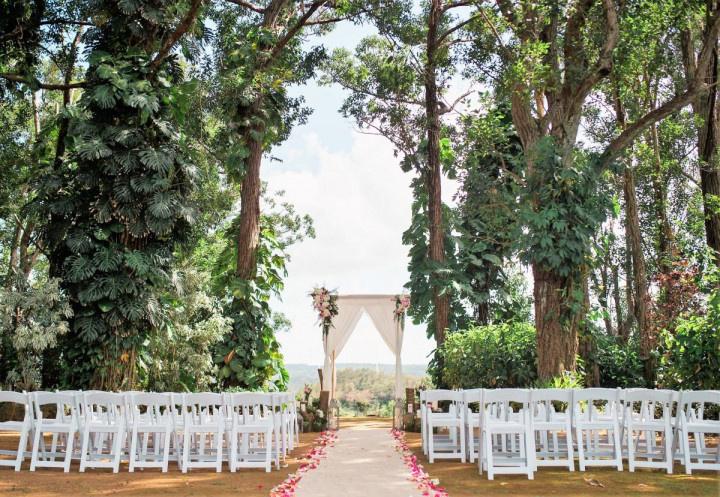 scenic outdoor wedding ceremony beneath shady trees on top of a hill overlooking the valley and ocean in the distance