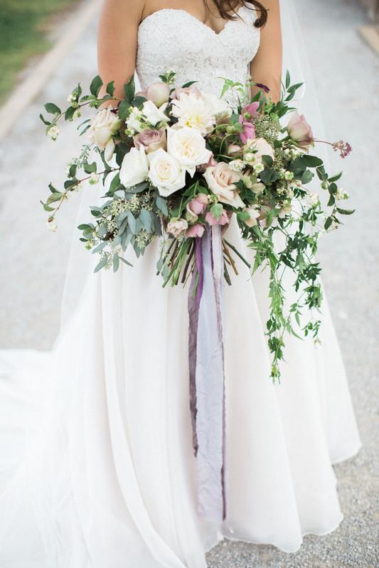 oversized wedding bouquet with white flowers, greenery and long purple ribbons