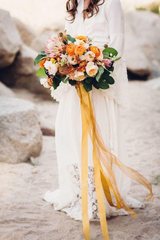 colorful yellow and peach wedding bouquet with garden roses, ranunculus and king protea