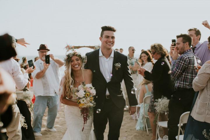 bride and groom smiling while walking down the aisle at beach wedding ceremony in Santa Barbara