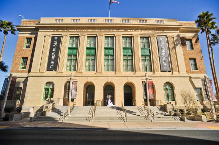 bride and groom kiss while standing on the steps of The Mob Museum in Las Vegas