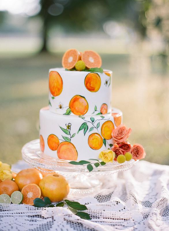 white fondant wedding cake with handpainted oranges and fresh orange slice topper