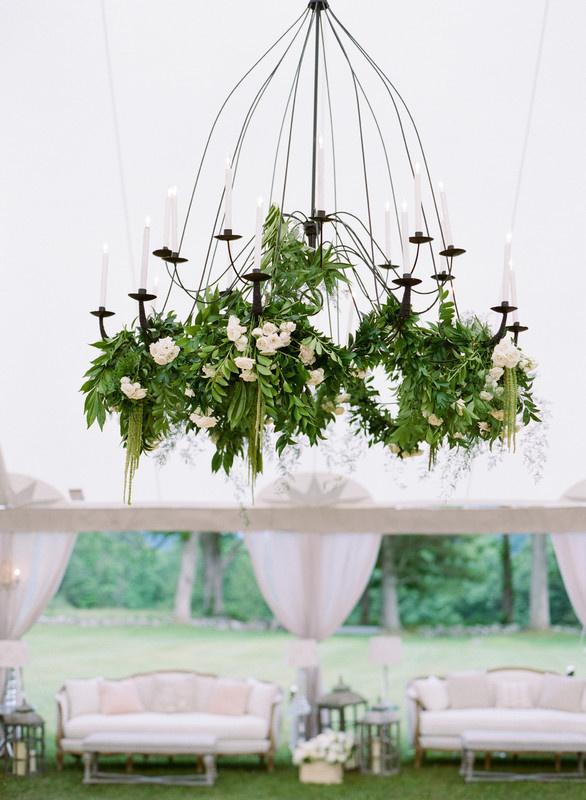 iron chandelier is decorated with greenery and white flower garlands