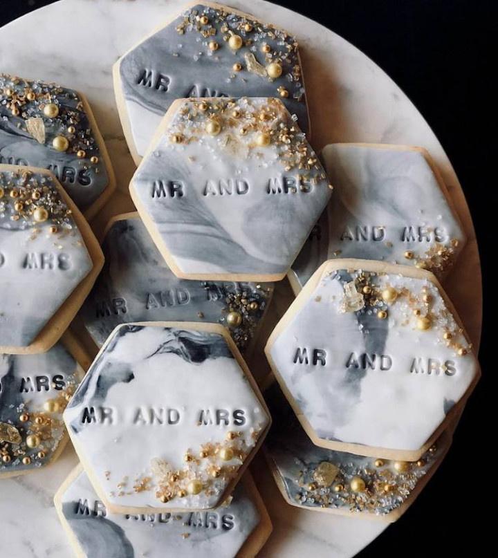 closeup of hexagonal-shaped cookies with swirled gray and white frosting and
