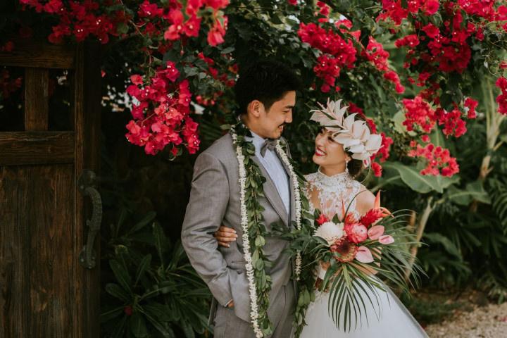 Hawaiian bride and groom wearing leis and smiling at each other