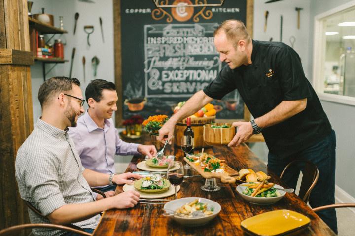 wedding caterer placing food in front of same-sex male couple at their catering tasting session