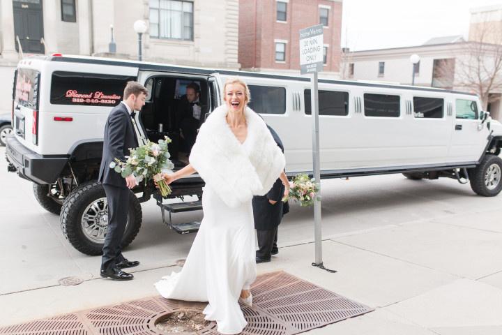 bride smiles as she exits a stretch hummer limousine at her wedding
