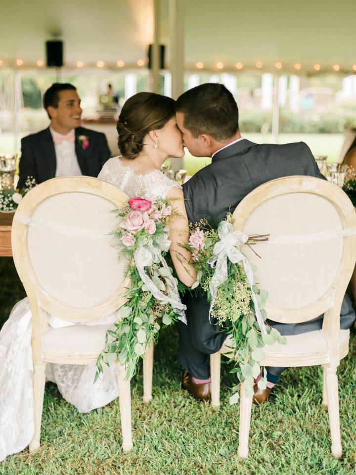 bride and groom kissing in decorated chairs 