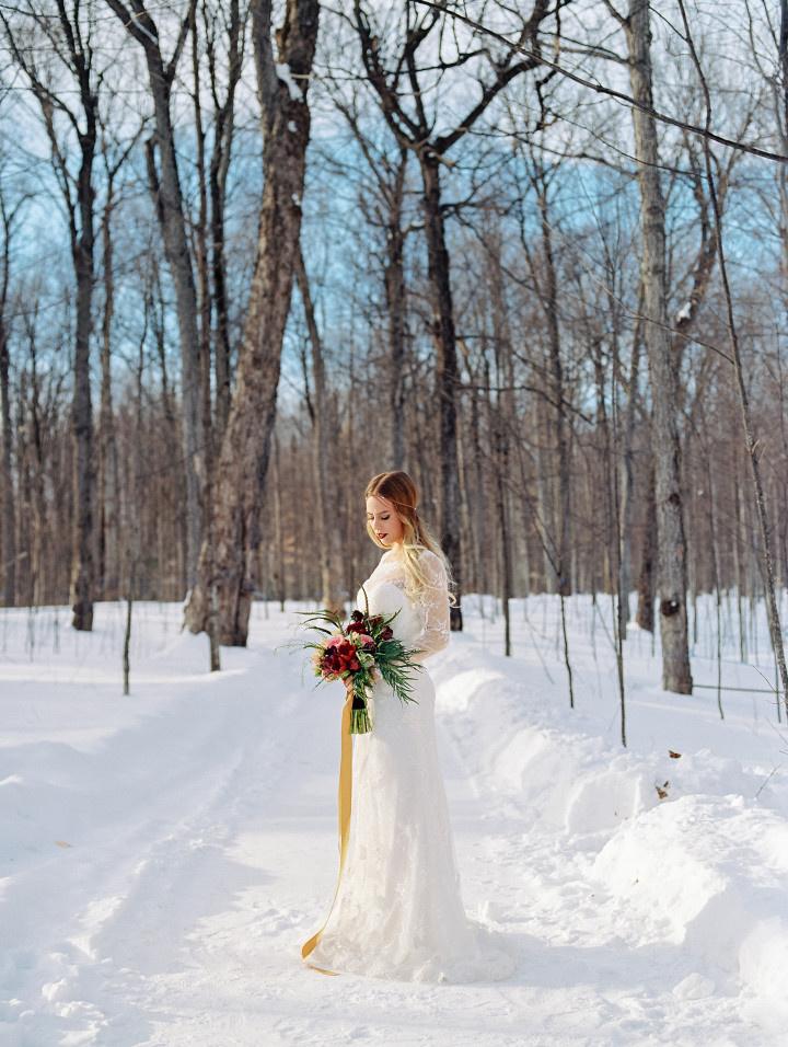 boho bridal portrait long sleeved lace sheath gown with illusion sleeves holding bouquet with caramel colored ribbon 