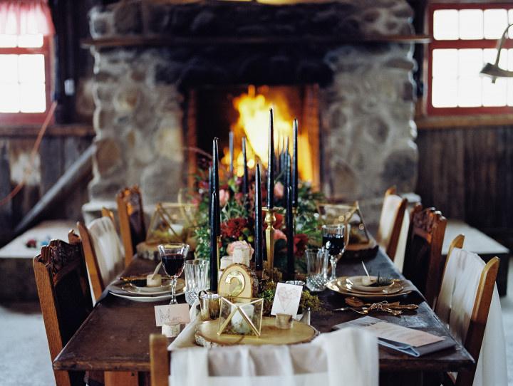 rustic tablescape navy hued candles floral centerpiece wood slices in front of stone fireplace 