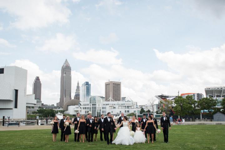 formal wedding party poses in a park in downtown cleveland with skyline in the background