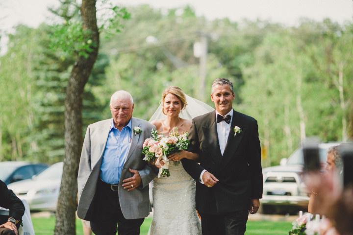 bride with father and stepfather walking down aisle 