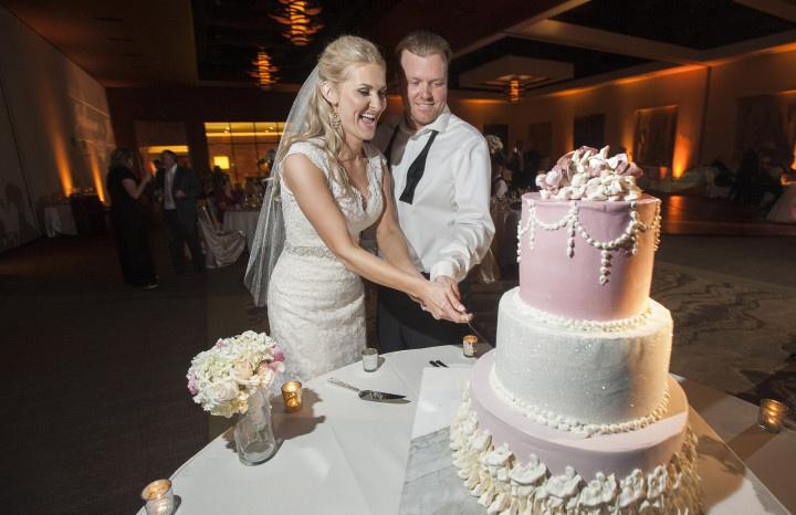 married couple cutting pink wedding cake