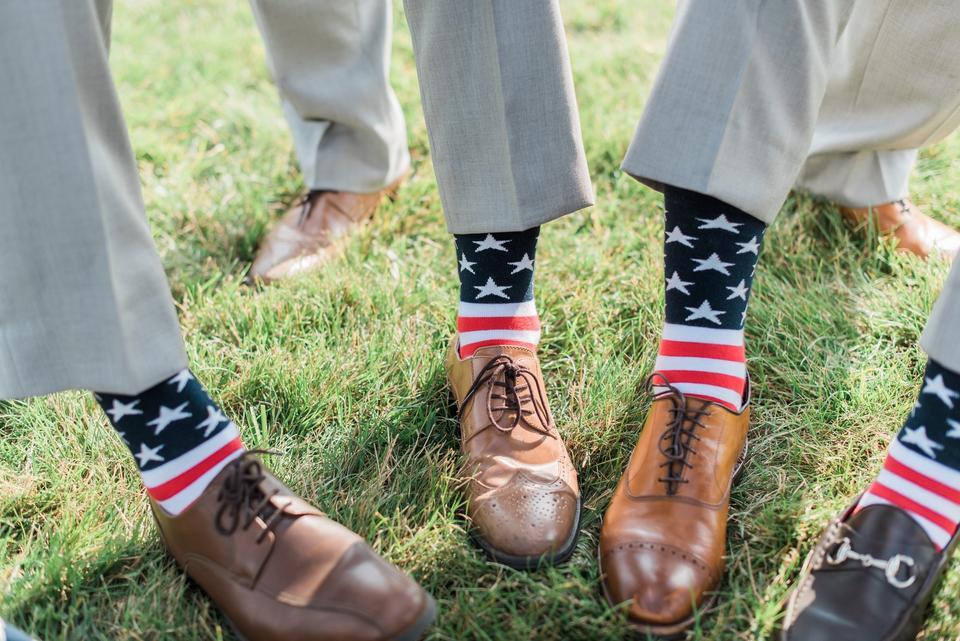 groomsmen showing their american flag socks with red white and blue summer wedding color scheme