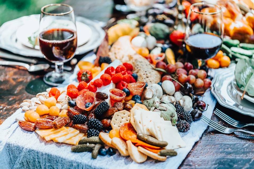 charcuterie board on table with glasses of red wine