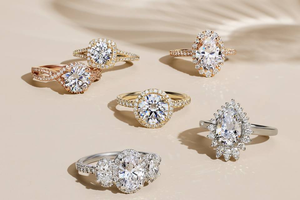 six engagement rings showcasing 2022 engagement ring trends in various styles against beige backdrop