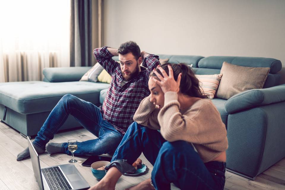 stressed out couple sitting on floor in front of computer