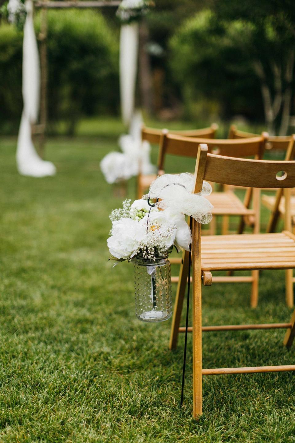 simple outdoor wedding aisle decor idea glass hobnail jar with white flowers and baby's breath displayed on small shepherd's hook