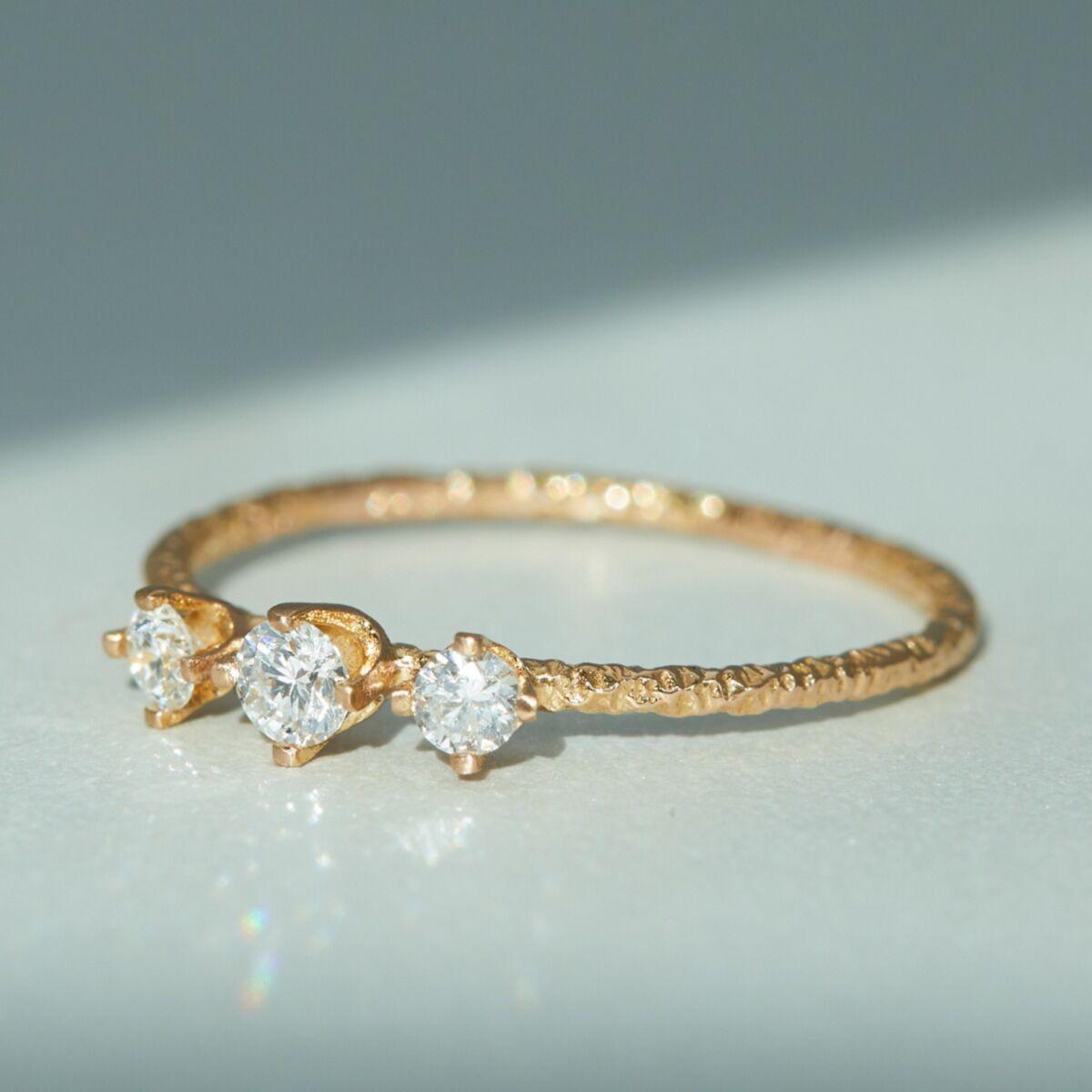 Dainty three-stone engagement ring with textured yellow gold band