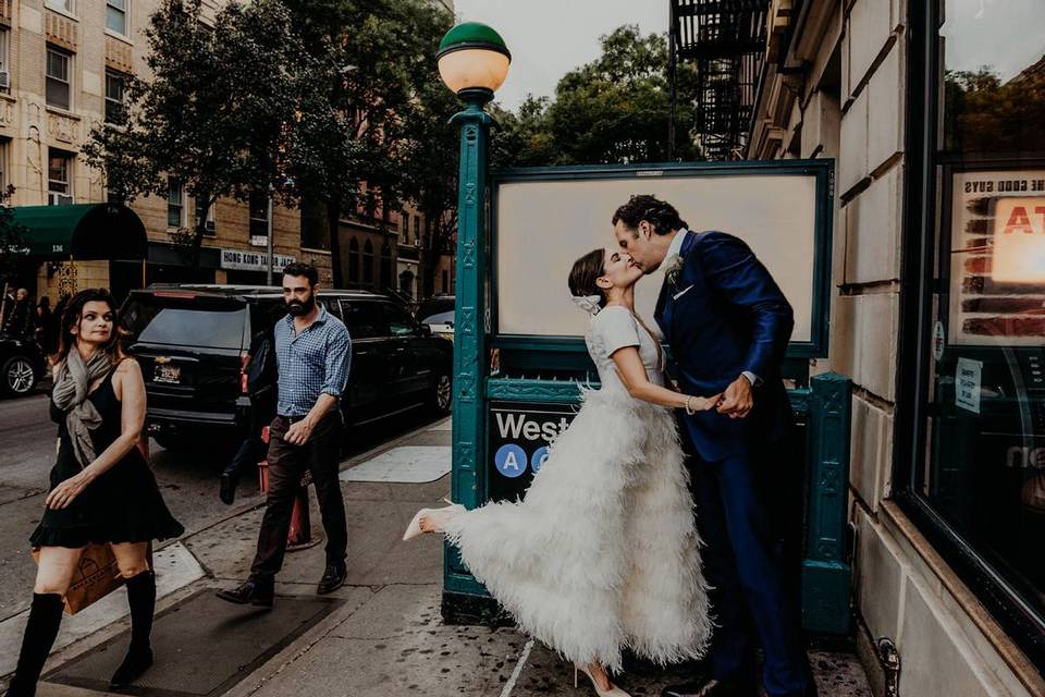 bride and groom kissing outside of nyc subway station