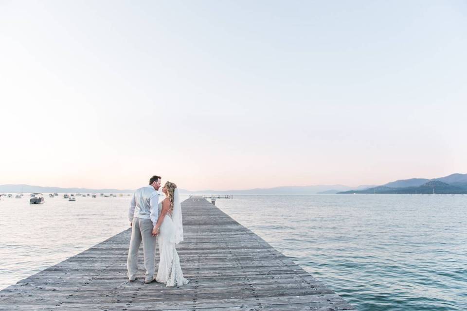 bride and groom walking along a long wooden dock on lake tahoe