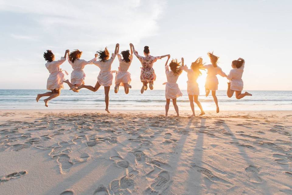 women holding hands and jumping on the beach