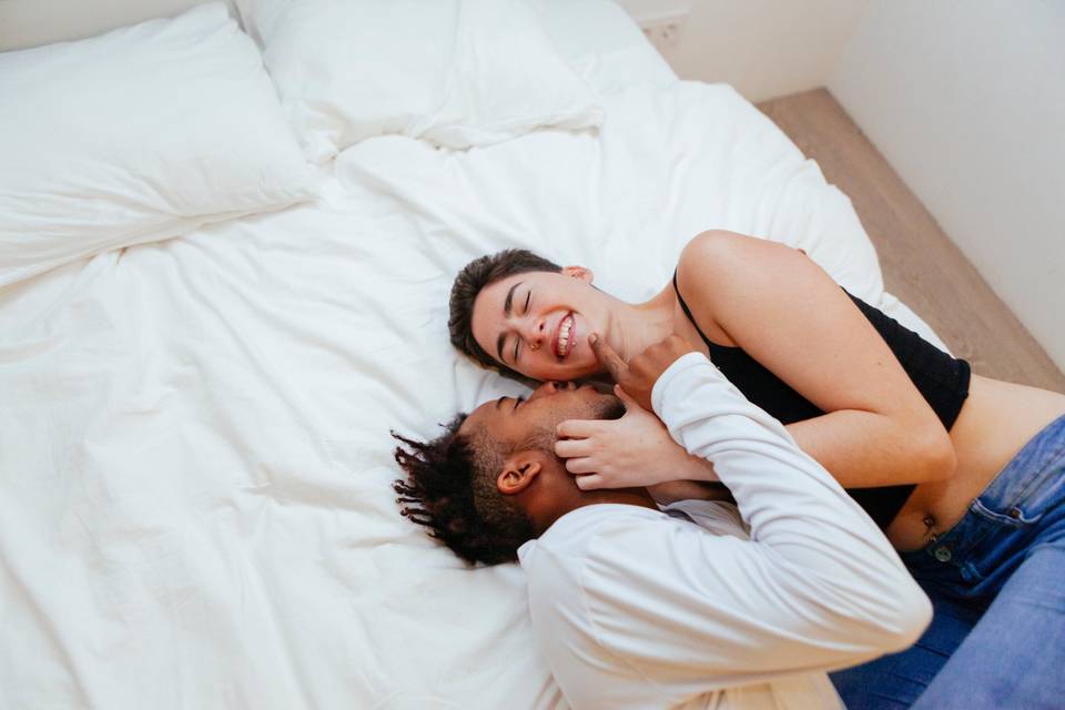 happy couple laughing while kissing on bed