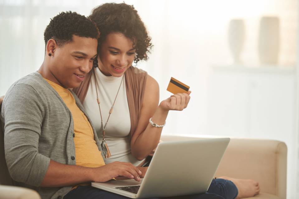 couple looking at computer while holding credit card