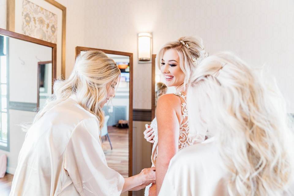 Bridesmaids helping bride into her wedding dress after putting on wedding undergarments