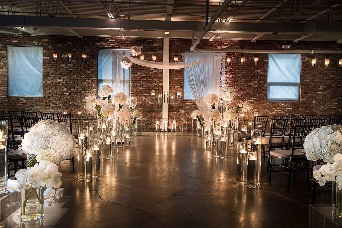 indoor wedding ceremony with brick wall backdrop white flowers and string lights