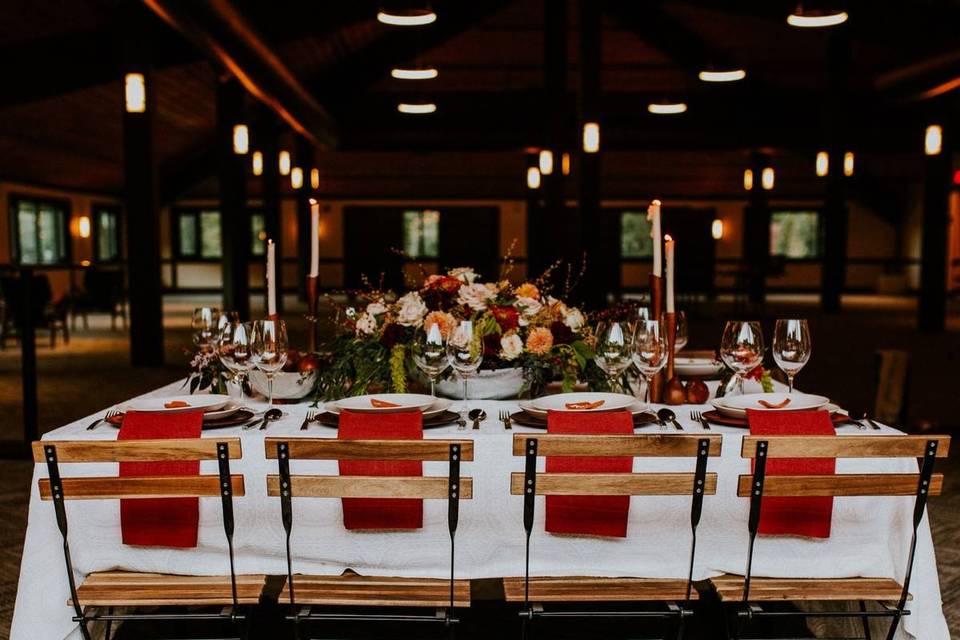 winter wedding theme reception table with white tablecloth, red napkins and tall candles