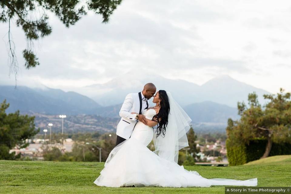 Black couple poses in formal attire outside at wedding venue with hills and mountain views in the background
