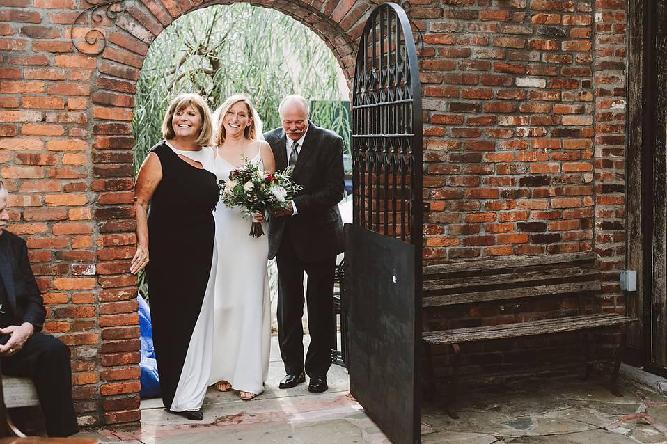 bride flanked by parents walking down the aisle