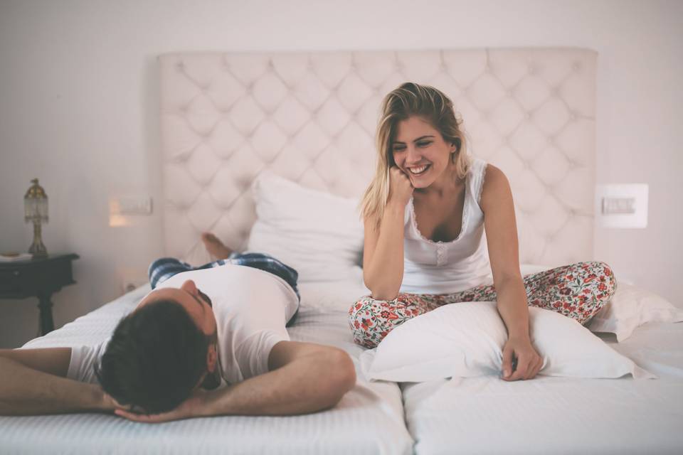 couple having a conversation in pajamas while sitting on bed