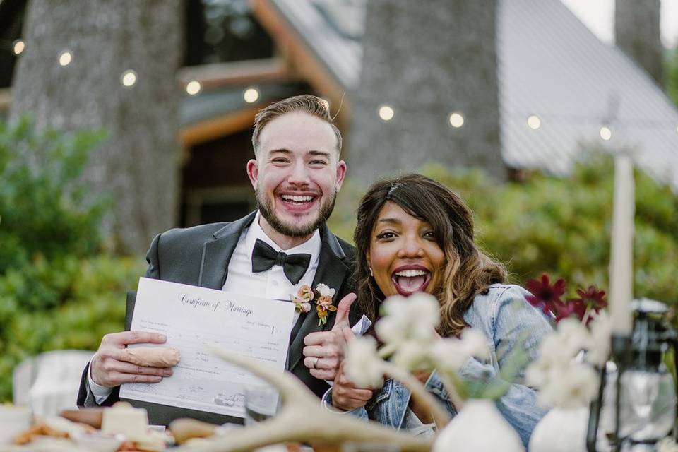 Interracial couple smiles and celebrates while holding their marriage certificate after covid wedding